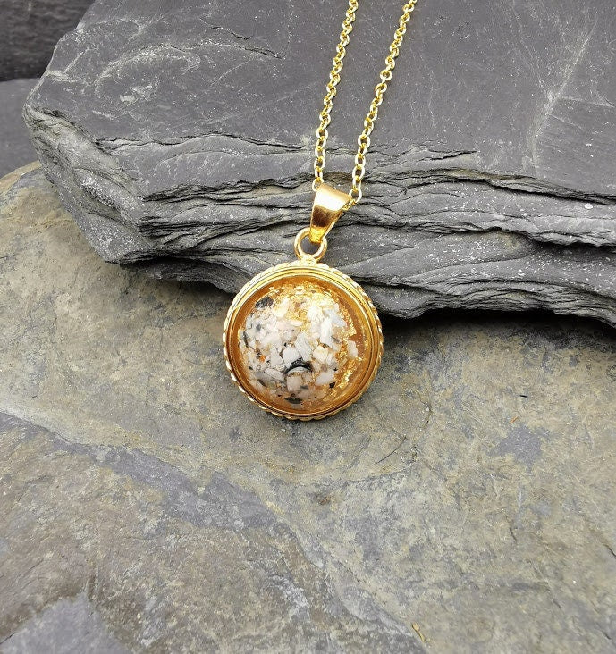 Goldener Dahlia-Anhänger mit Asche-Einschluss an Goldkette auf Schieferstein, Seitenansicht – Ascheschmuck von Zinou Minimanufaktur