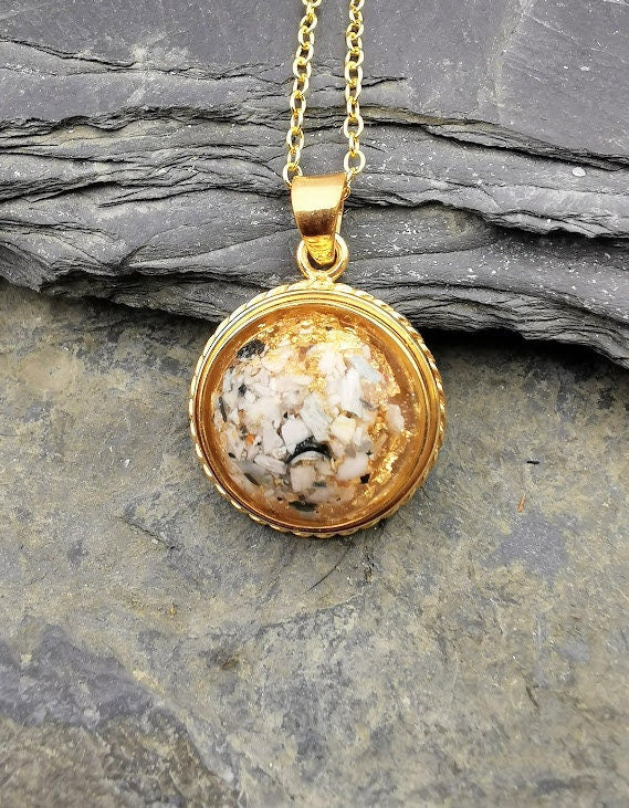 Goldener Dahlia-Anhänger mit weißem Asche-Einschluss auf Schieferstein, Nahaufnahme – Ascheschmuck von Zinou Minimanufaktur