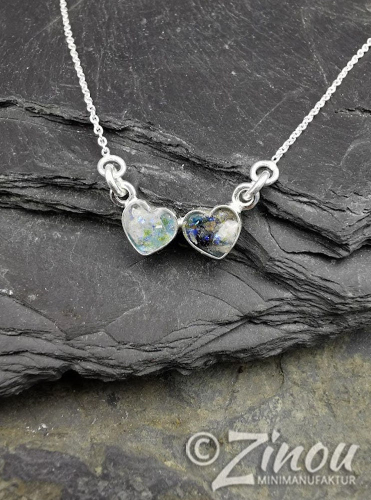 Zwei silberne Herzanhänger mit blau-grünem Asche-Einschluss an Silberkette auf Schieferstein – Gedenkschmuck von Zinou Minimanufaktur