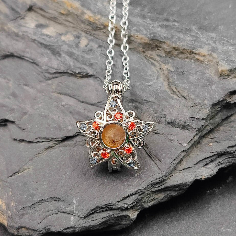 Silberner Engelrufer Blume mit goldfarbener Fellperle und orangefarbenen Zirkonia auf Schieferstein – Gedenkschmuck von Zinou Minimanufaktur