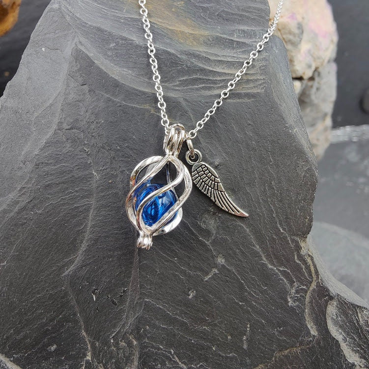 Engelrufer Sterling Silber mit blauer Glasperle und Flügel-Charm an Silberkette auf Schieferstein, Nahaufnahme – Gedenkschmuck DIY von Zinou Minimanufaktur