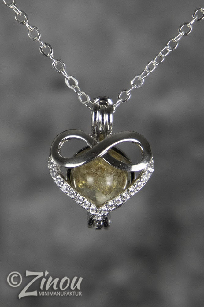 Engelsrufer Infinity-Herzanhänger mit Asche-Perle hängend an Silberkette, grauer Hintergrund – Gedenkschmuck von Zinou Minimanufaktur