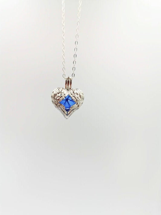 Silberner Herz-Käfig-Anhänger mit Engelflügeln und blauer Glasperle hängend an Silberkette – DIY Gedenkschmuck zum selber Füllen von Zinou Minimanufaktur