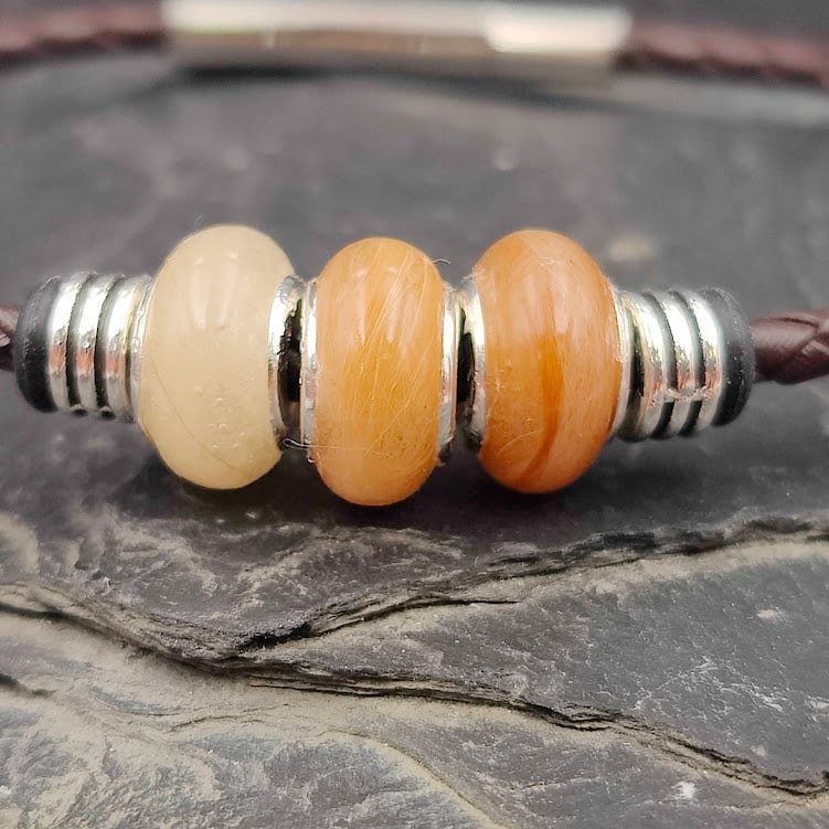 Nahaufnahme Glattlederarmband mit drei orangefarbenen Minifellperlen – Tierhaarschmuck von Zinou Minimanufaktur