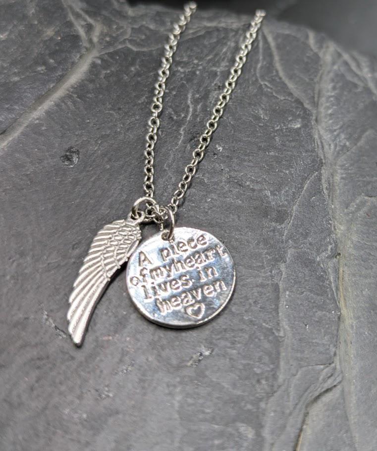 Silberne Heaven-Kette mit Flügel-Charm und graviertem Anhänger auf Schieferstein, Draufsicht – Gedenkschmuck von Zinou Minimanufaktur