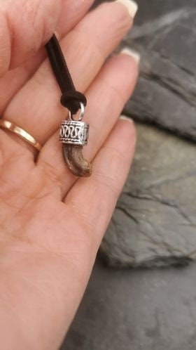 Heller Krallen-Anhänger mit silberner Fassung in Frauenhand vor Schieferstein – Tierschmuck von Zinou Minimanufaktur