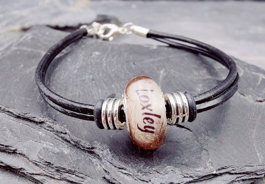 Schwarzes Lederarmband Lenni mit beige-brauner Fellperle und graviertem Namen „Loxley\" auf Schieferstein – Tierhaarschmuck von Zinou Minimanufaktur