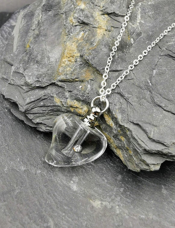 Klarer Glas-Herz-Urnenanhänger mit Strassstein an Silberkette auf Schieferstein, Nahaufnahme – Miniurne Gedenkschmuck von Zinou Minimanufaktur
