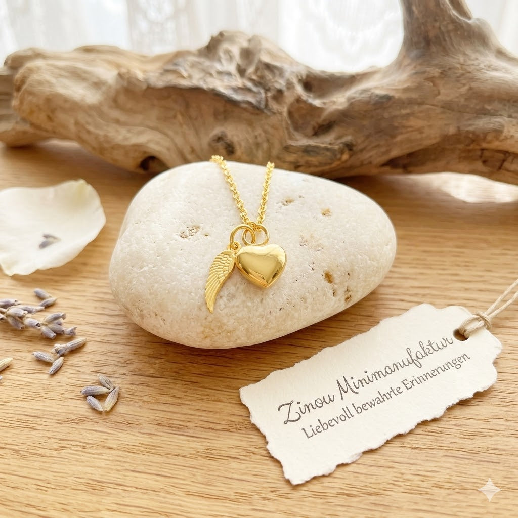 Goldene Miniurne Herz mit Flügel-Charm an Goldkette auf hellem Stein mit Lavendel und Treibholz, Zinou-Kärtchen – Gedenkschmuck von Zinou Minimanufaktur