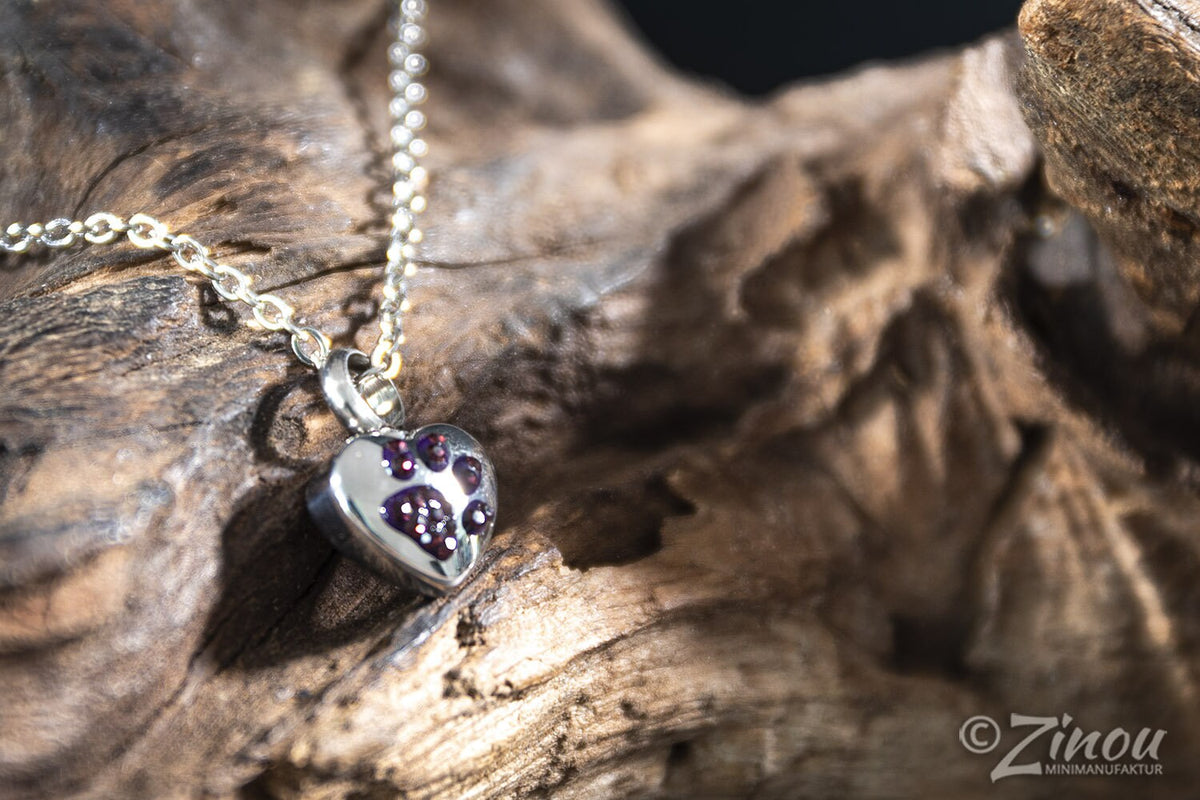 Silberne Herz-Miniurne mit lila Strass-Pfötchen-Motiv an Silberkette auf Treibholz – Gedenkschmuck von Zinou Minimanufaktur