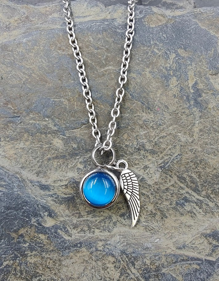 Miniurnen-Anhänger Leni mit türkisblauer Kugel und Flügel-Charm an Silberkette auf Schieferstein, Frontansicht – Gedenkschmuck von Zinou Minimanufaktur