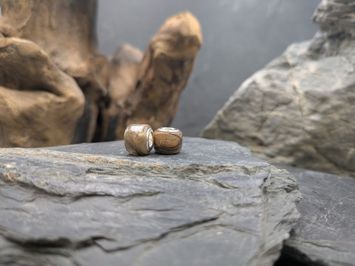 Zwei eckige Großlochperlen gefüllt mit Fell auf Schieferstein vor Treibholz, Nahaufnahme – Tierhaarschmuck von Zinou Minimanufaktur