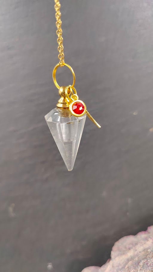 Pendel-Urne aus Bergkristall in Pendelform mit Flügel-Charm und rotem Kristallstein an Goldkette auf Schieferstein Gedenkschmuck von Zinou Minimanufaktur