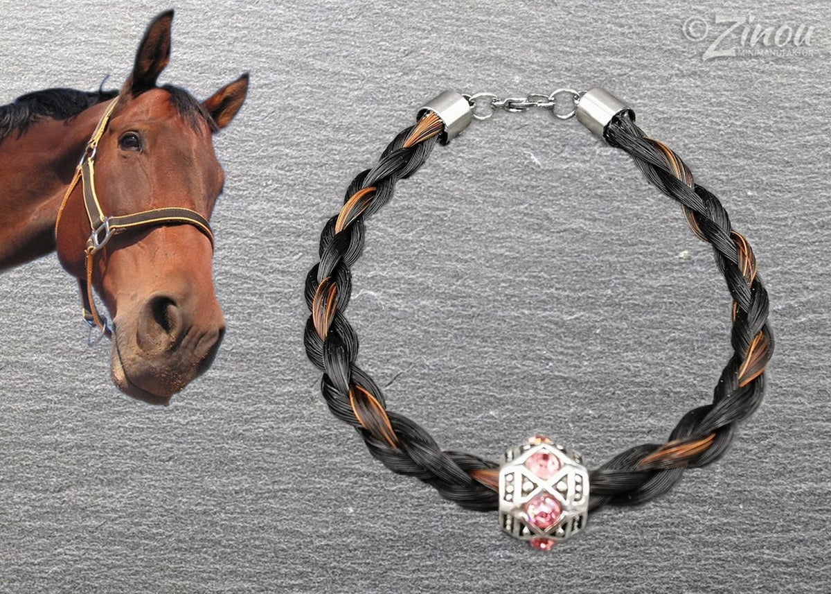 Geflochtenes schwarz-braunes Pferdehaararmband mit silberner Perle und rosafarbenen Strasssteinen auf grauem Hintergrund, braunes Pferd im Bild – Pferdehaarschmuck von Zinou Minimanufaktur