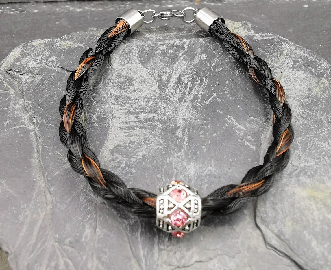 Geflochtenes schwarz-braunes Pferdehaararmband mit silberner Perle und rosafarbenen Strasssteinen auf Schieferstein, Draufsicht – Pferdehaarschmuck von Zinou Minimanufaktur