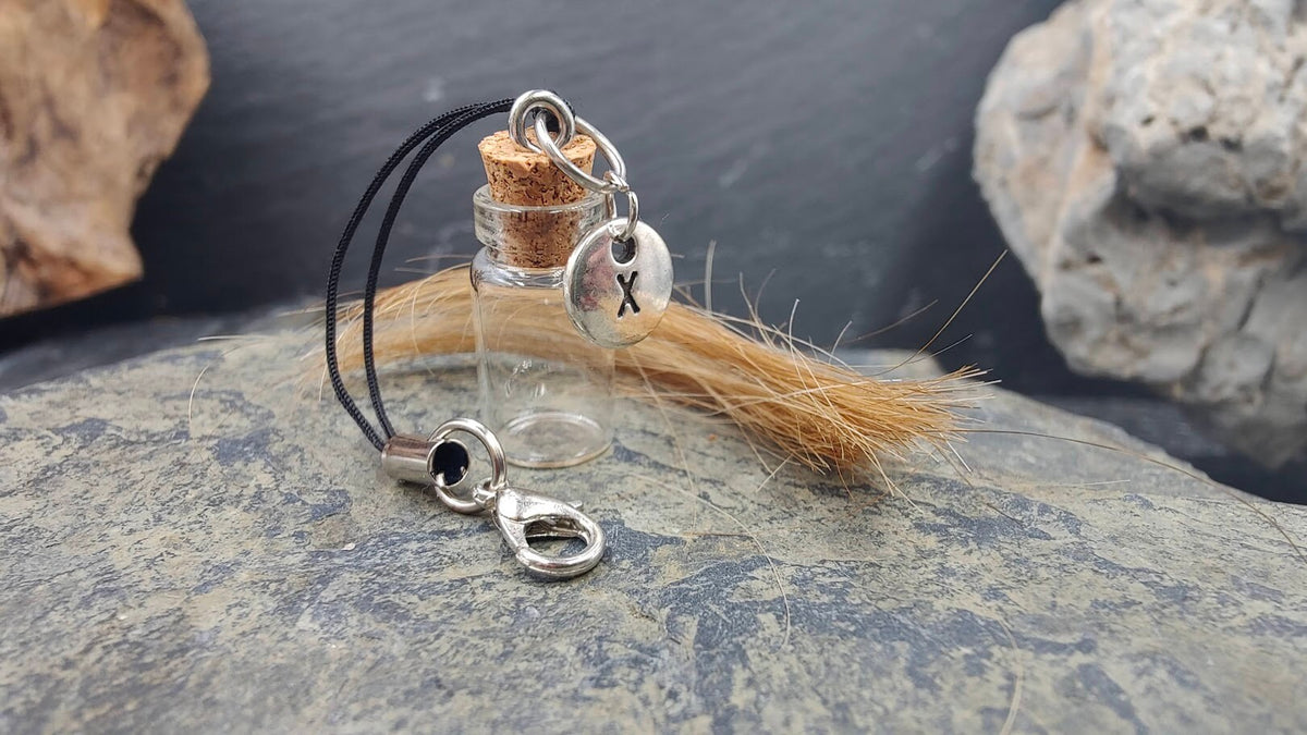 Glasphiole mit Buchstaben-Charm auf Naturstein mit Pferdehaar daneben – Erinnerungsschmuck DIY von Zinou Minimanufaktu