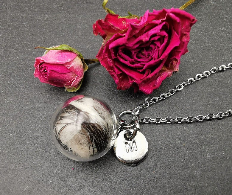 Glasphiole mit Tierhaar und silbernem Buchstaben-Charm M an Silberkette neben getrockneten roten Rosen auf Schieferstein – personalisierter Gedenkschmuck von Zinou Minimanufaktur