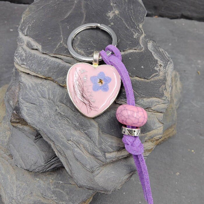Personalisierter rosafarbener Herz-Schlüsselanhänger mit Tierhaar und blauer Vergissmeinnicht-Blüte an lila Kordel mit rosa Perle auf Schieferstein – Gedenkschmuck von Zinou Minimanufaktur