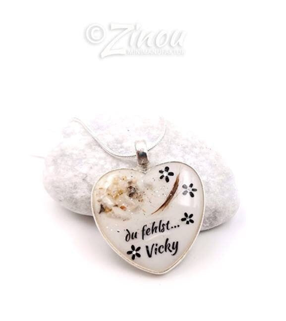 Personalisierter weißer Herz-Anhänger mit Tierhaar, Blütenmotiv und Aufschrift du fehlst Vicky an Silberkordel auf weißem Kieselstein – Gedenkschmuck von Zinou Minimanufaktur