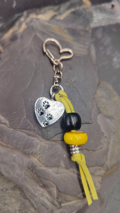 Silberner Herz-Schlüsselanhänger mit Pfotenabdrücken und gelber Perle an gelbem Lederband mit herzförmigem Karabiner auf Schieferstein – Gedenkschmuck von Zinou Minimanufaktur