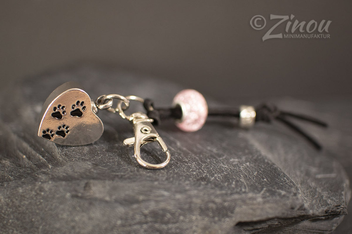 Silberner Herz-Urnen-Charm mit Pfotenabdrücken und rosa Perle an schwarzem Lederband auf Schieferstein – Gedenkschmuck von Zinou Minimanufaktur