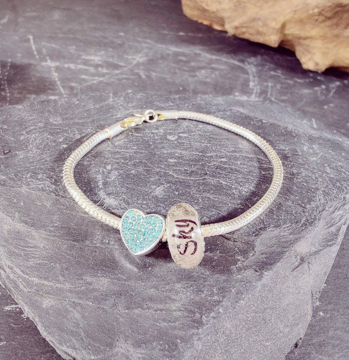 Sterling Silber Armband mit gravierter Fellperle mit Name Sky und türkisem Strass-Herzanhänger auf Schieferstein, Draufsicht – personalisierter Gedenkschmuck von Zinou Minimanufaktur
