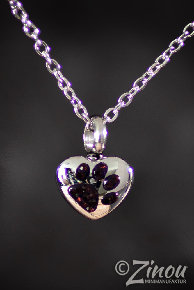 Silberne Herzurne mit Kette hängend mit Strass Pfotenabdruck schwarzer Hintergrund