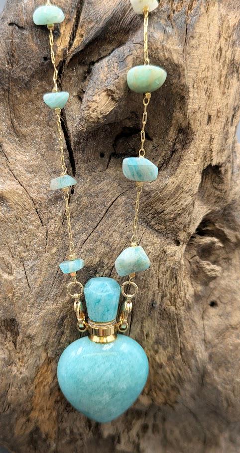 Herzurnen-Anhänger aus Türkis mit Türkis-Perlen an Goldkette hängend an Treibholz, Frontansicht – Gedenkschmuck von Zinou Minimanufaktur