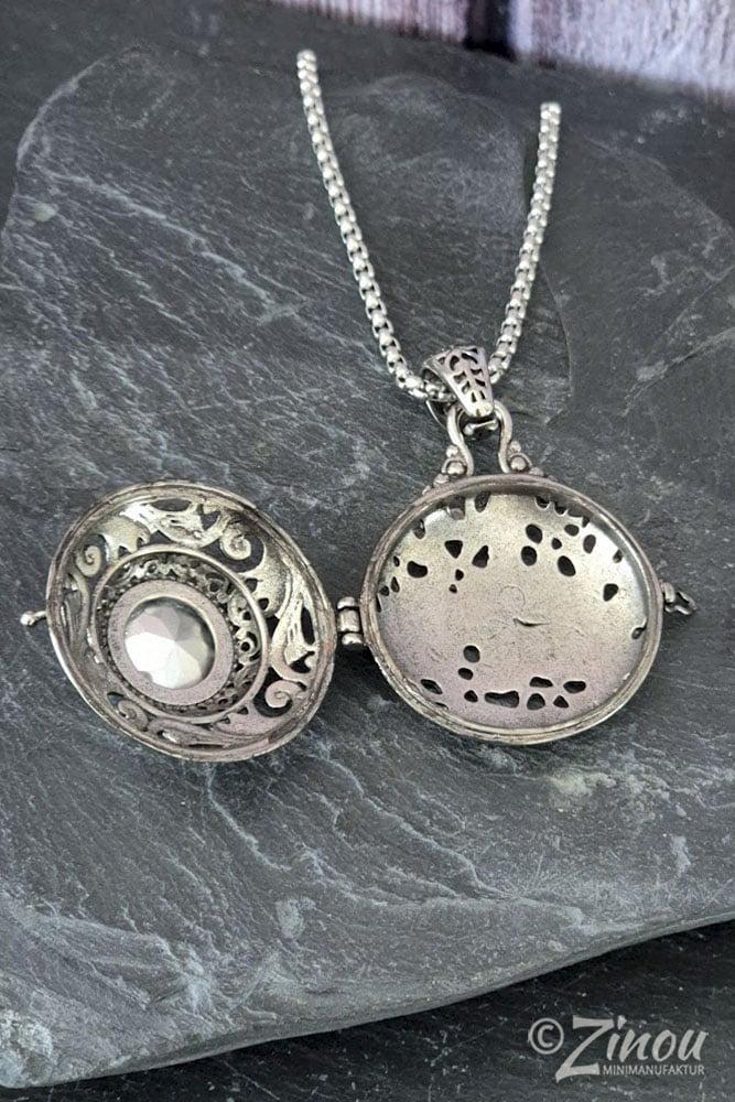 Silbernes Amulett „Smaragd" aufgeklappt auf Schieferstein – Innenraum zum Selbstbefüllen mit Fell, Asche oder Andenken sichtbar – Zinou Minimanufaktur