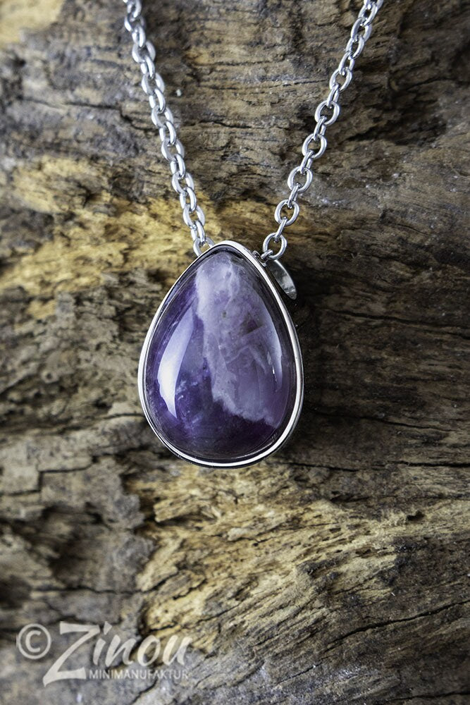 Silberner Tropfen-Urnenanhänger mit violettem Amethyst-Halbedelstein an Silberkette auf Treibholz – Gedenkschmuck von Zinou Minimanufaktur