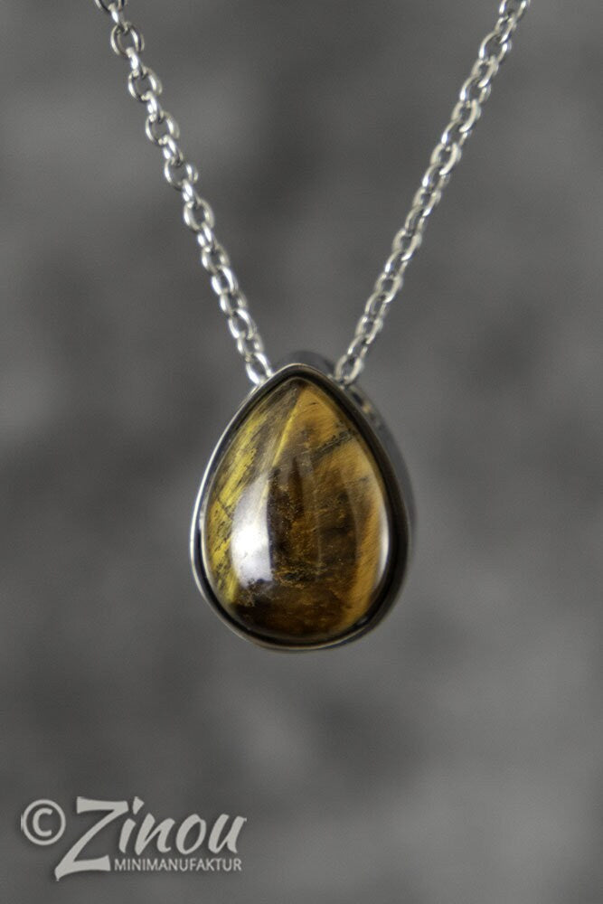 Silberner Tropfen-Urnenanhänger mit goldenem Tigerauge-Halbedelstein an Silberkette vor grauem Hintergrund – Gedenkschmuck von Zinou Minimanufaktur