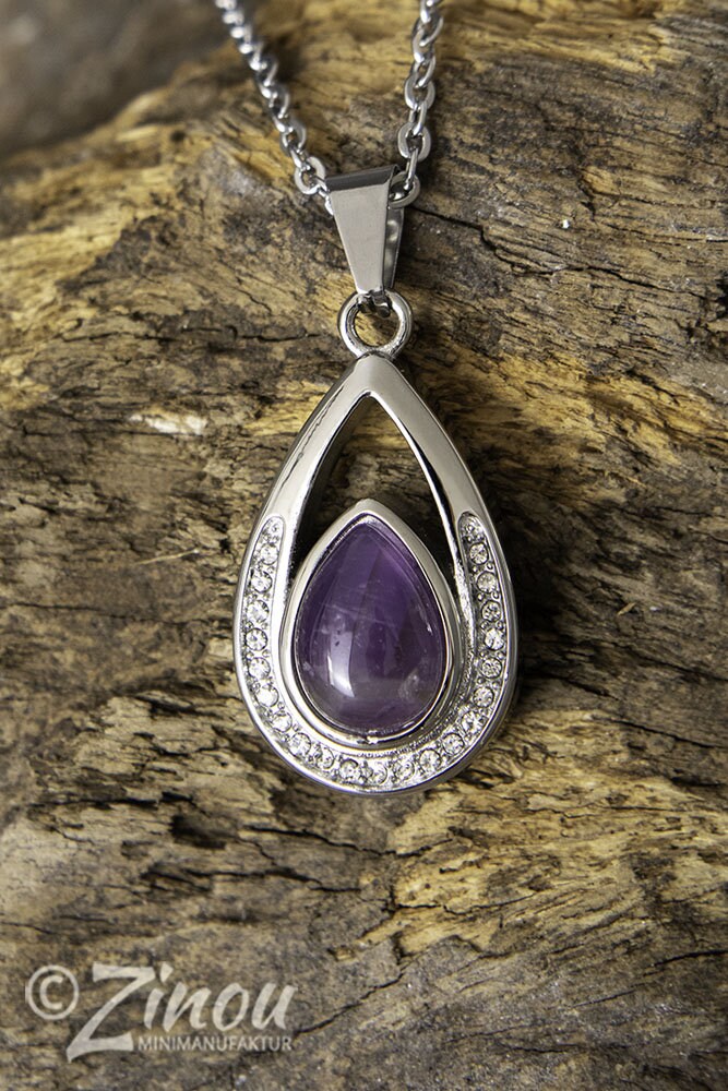 Silberner Tropfen-Urnenanhänger mit lila Amethyst und Strasssteinen hängend an Silberkette auf Holz – Gedenkschmuck von Zinou Minimanufaktur