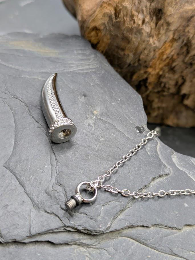 Silberner Wolfszahn-Urnenanhänger aufgeschraubt auf Schieferstein, Befüllöffnung für Asche oder Fell sichtbar – Gedenkschmuck von Zinou Minimanufakt