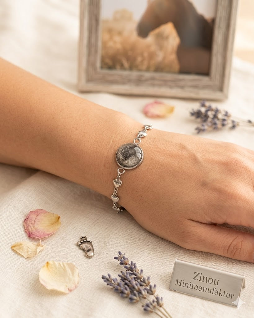 Arm liegt auf dem Tisch mit einem silbernem Armband gefüllt mit Fell unten steht ein silbernes Schild mit der Aufschrift Zinou Minimanufaktur