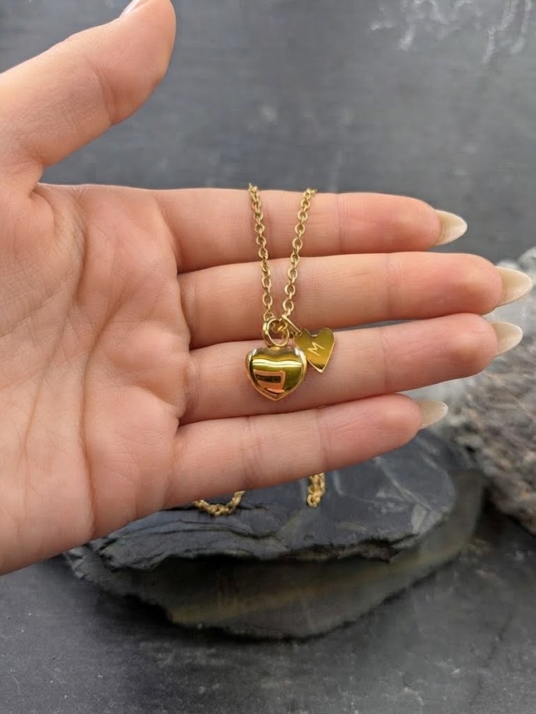 hand hält goldene Urne mit Buchstabe M Hintergrund ist aus Schiefer